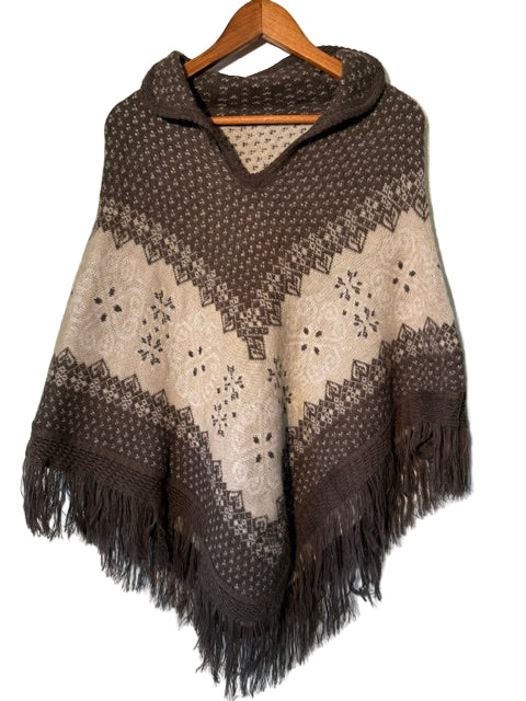 Brown and beige patterned poncho with fringe on a hanger against a white background